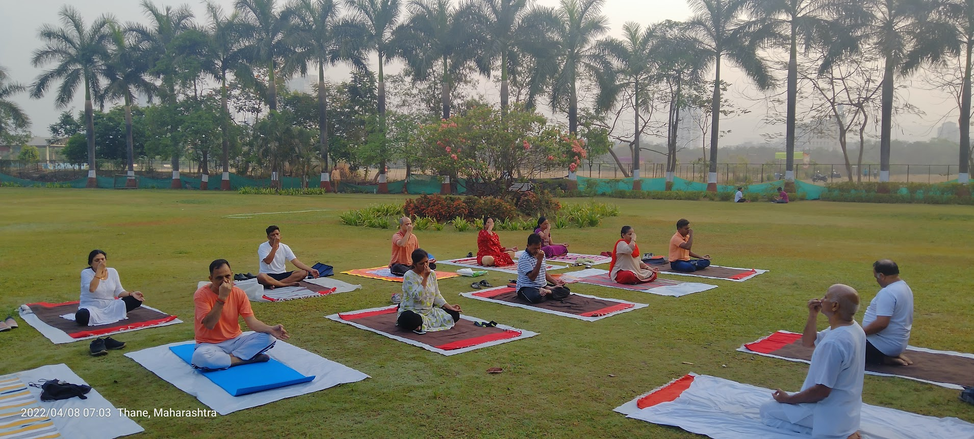 A group of students practicing breathing exercises on an open lawn